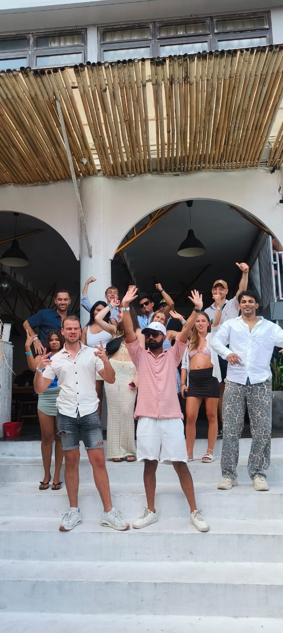 The whole group cheering on the steps of a beach cafe